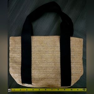 Small lined tan woven tote bag with black handles